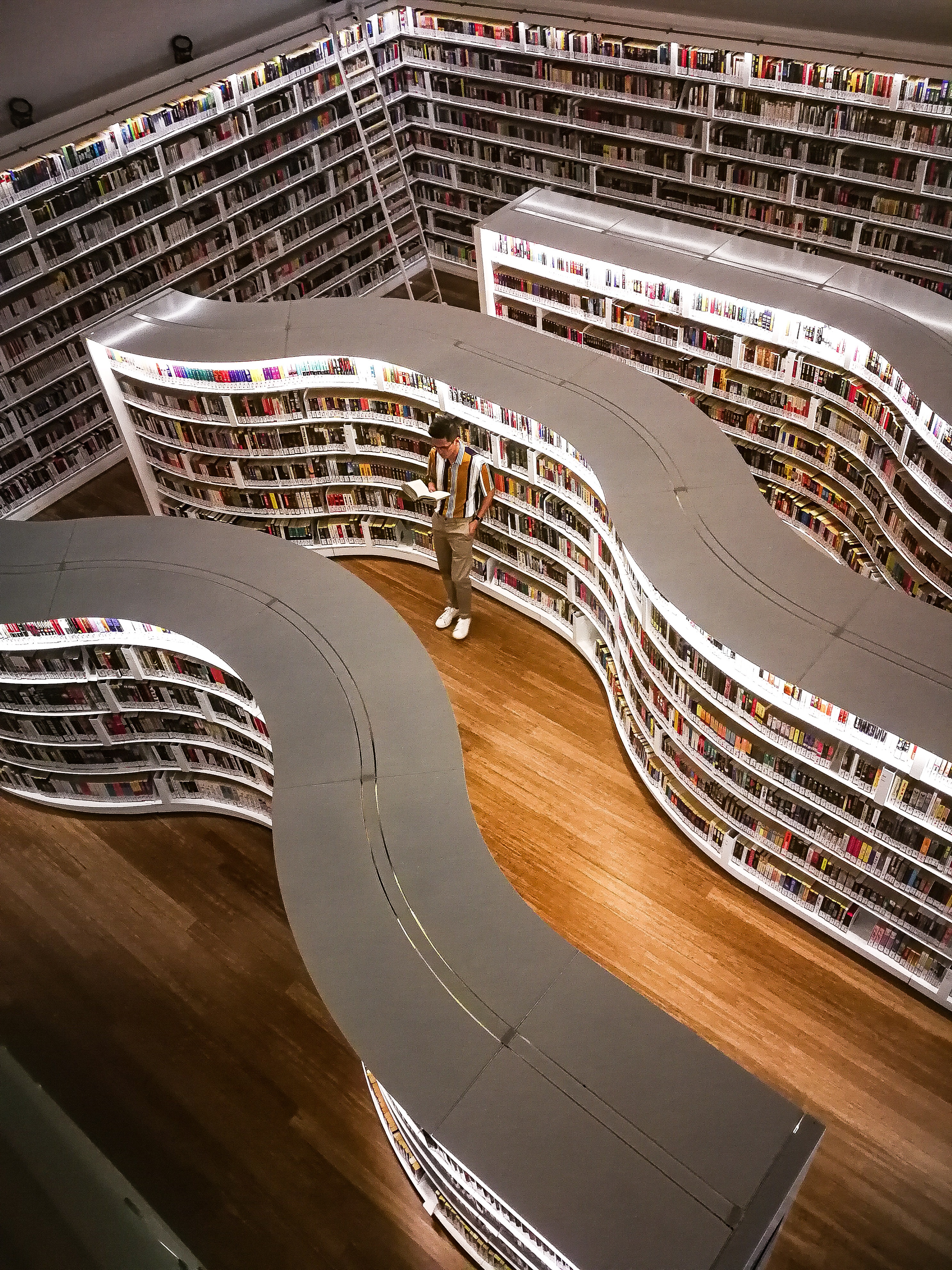 man-standing-inside-library-while-reading-book-3494806
