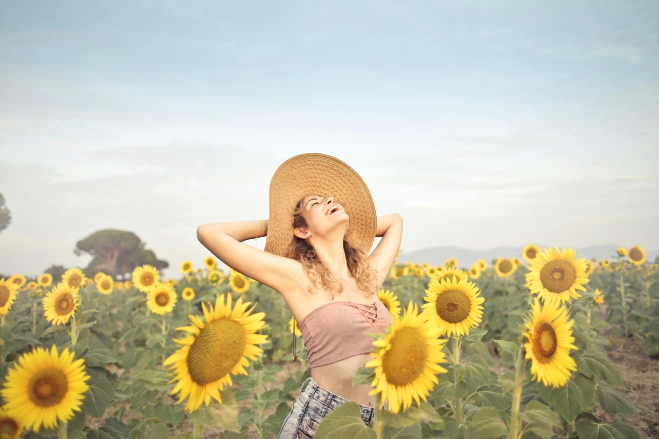A woman in a field of sunflowers looking at the sky.