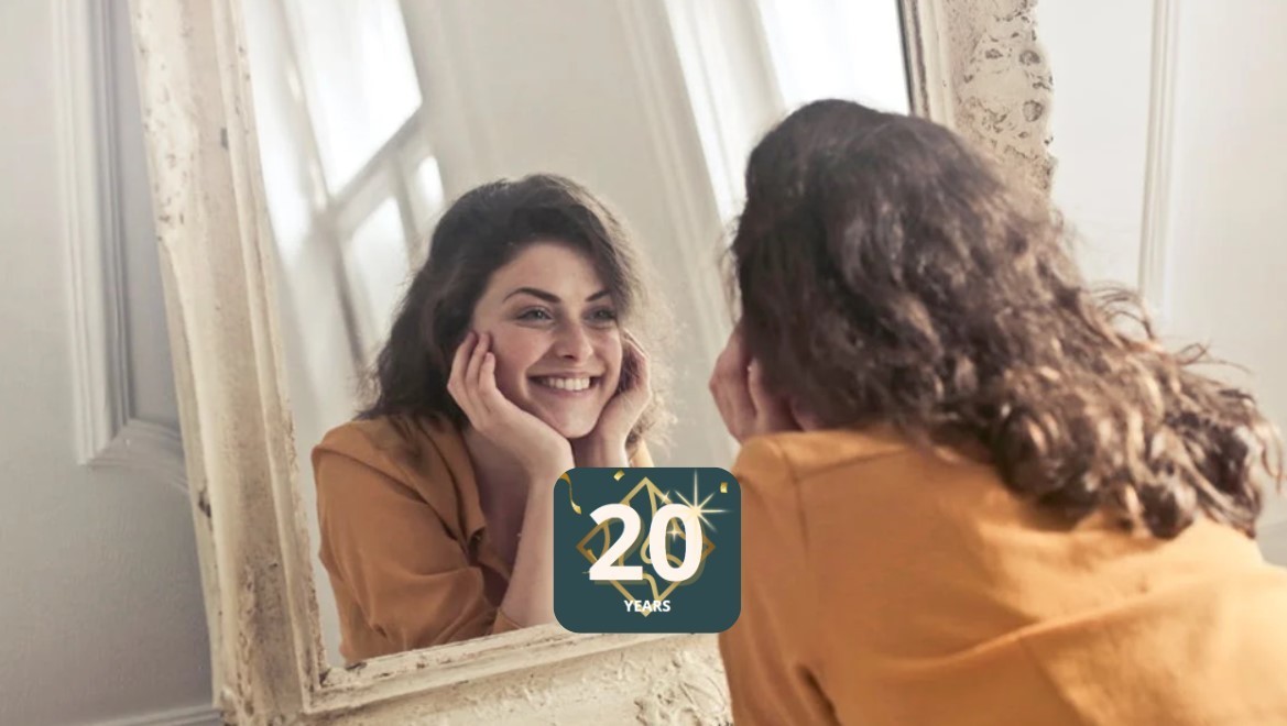 A woman smiling into the mirror 20 years.